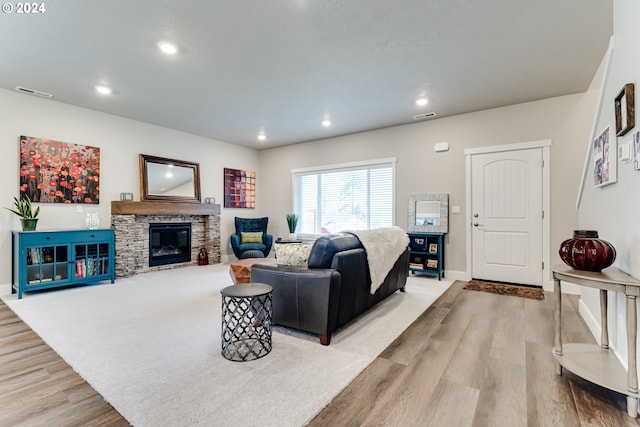 living room featuring a stone fireplace and light wood-type flooring