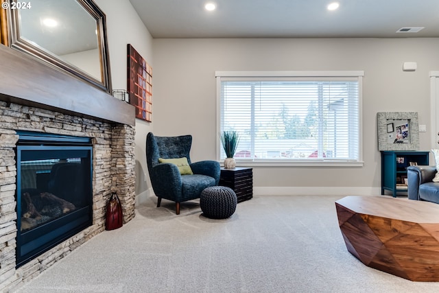 sitting room with a stone fireplace and carpet