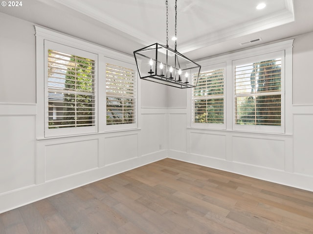 unfurnished dining area with hardwood / wood-style floors, a healthy amount of sunlight, a notable chandelier, and a tray ceiling