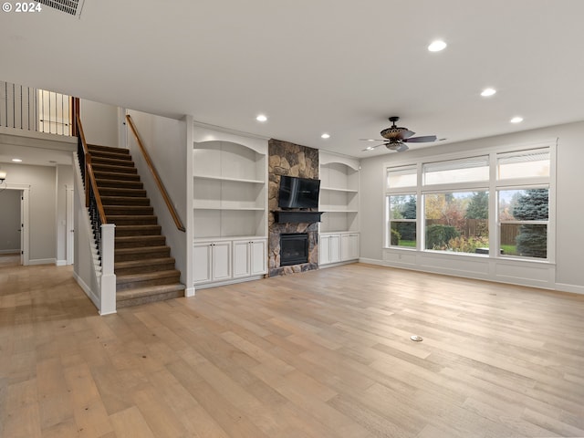 unfurnished living room featuring built in features, light wood-type flooring, ceiling fan, and a fireplace