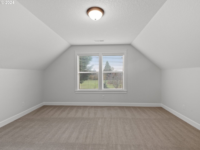 bonus room featuring a textured ceiling, light carpet, and lofted ceiling