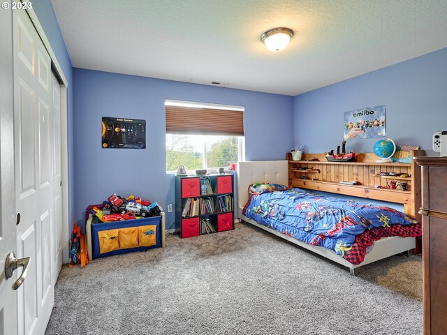 carpeted bedroom with a closet and a textured ceiling