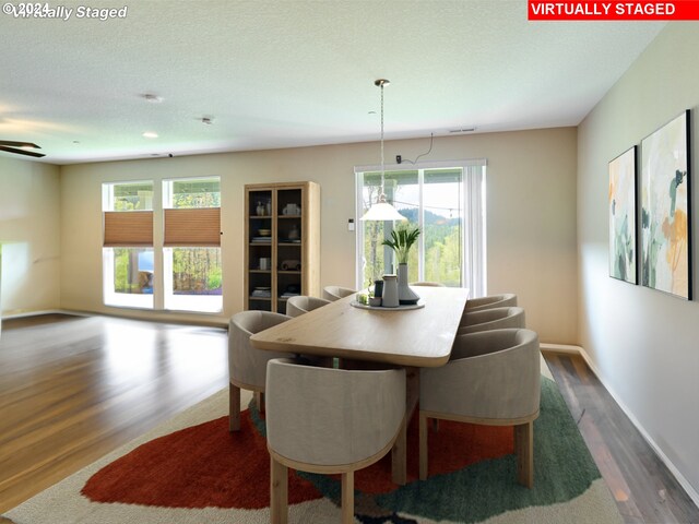 dining space with ceiling fan, a textured ceiling, and dark hardwood / wood-style flooring