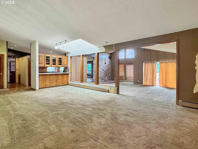 unfurnished living room featuring track lighting, a baseboard heating unit, light carpet, sink, and a textured ceiling