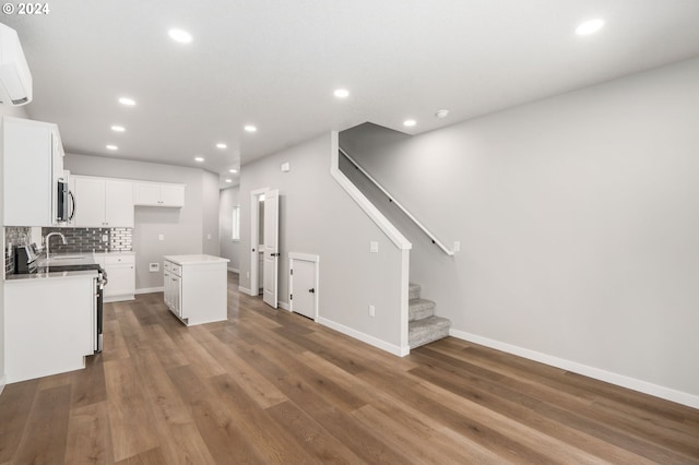 kitchen with white cabinetry, a kitchen island, dark hardwood / wood-style flooring, backsplash, and a wall mounted AC