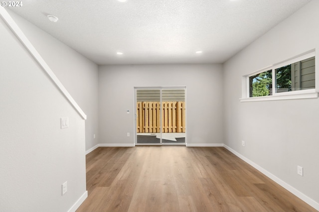 spare room with light hardwood / wood-style flooring and a textured ceiling