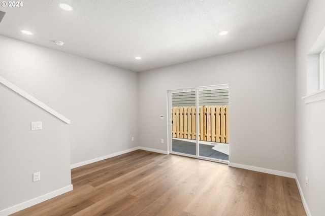 unfurnished room with hardwood / wood-style floors and a textured ceiling