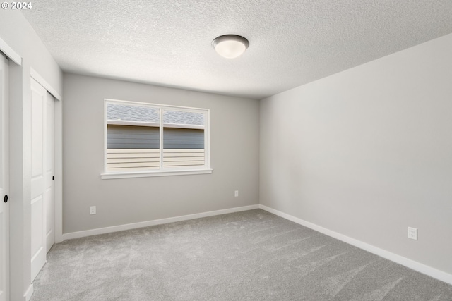 spare room featuring light colored carpet and a textured ceiling