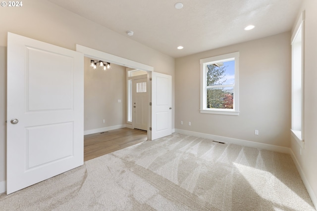 unfurnished bedroom with light colored carpet and an inviting chandelier