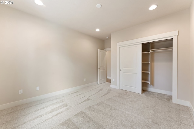 unfurnished bedroom with light colored carpet and a closet