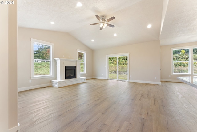 unfurnished living room with ceiling fan, light hardwood / wood-style floors, lofted ceiling, and a textured ceiling