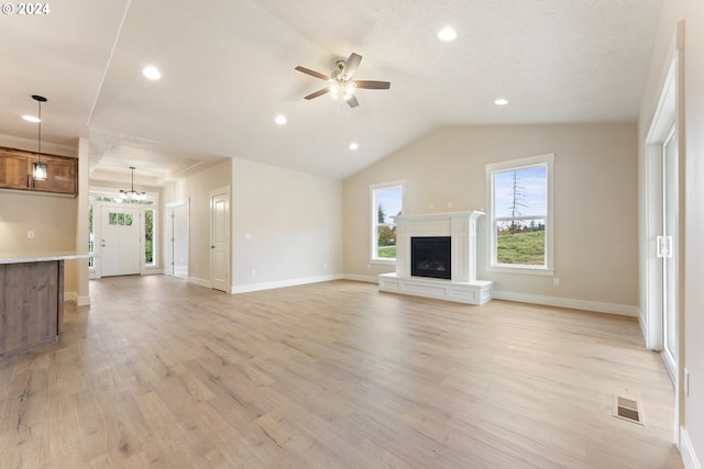 unfurnished living room featuring ceiling fan with notable chandelier, light hardwood / wood-style flooring, and lofted ceiling