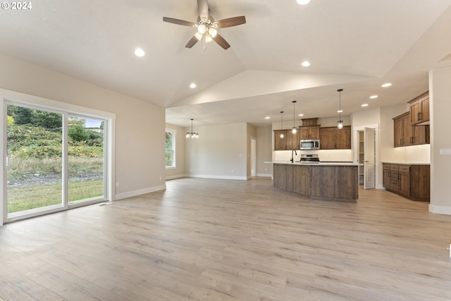 unfurnished living room featuring ceiling fan with notable chandelier, light wood-type flooring, vaulted ceiling, and sink