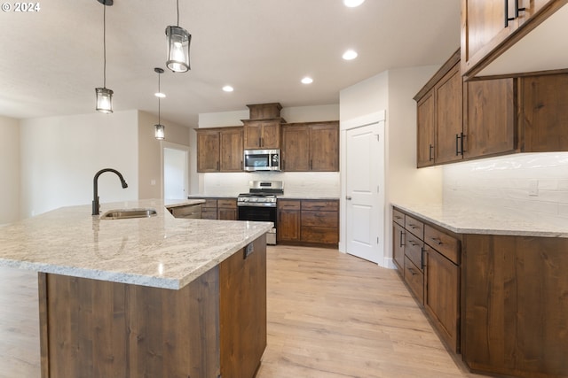 kitchen featuring pendant lighting, a spacious island, sink, appliances with stainless steel finishes, and light hardwood / wood-style floors