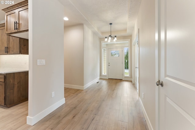 entryway featuring a textured ceiling, light hardwood / wood-style floors, and an inviting chandelier