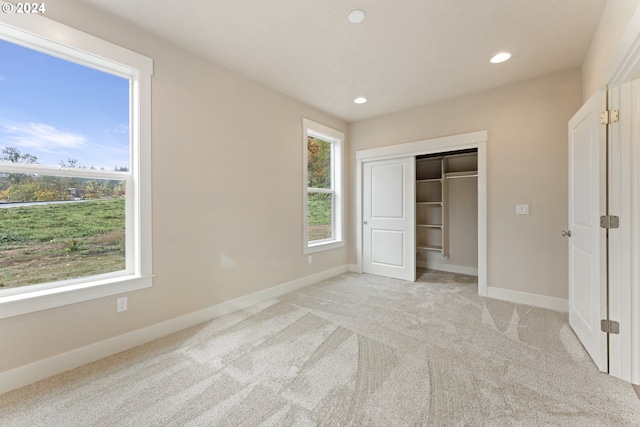 unfurnished bedroom with light colored carpet and a closet