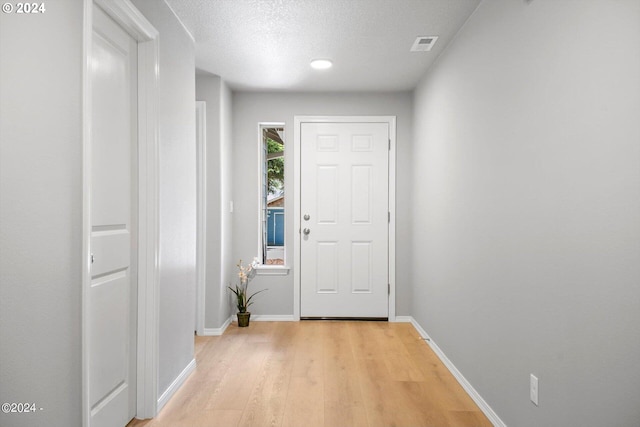 entryway with a textured ceiling and light hardwood / wood-style floors