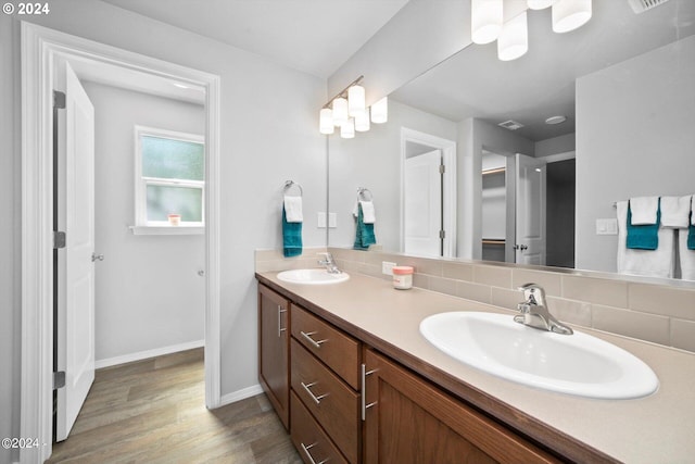 full bathroom with decorative backsplash, double vanity, wood finished floors, and a sink