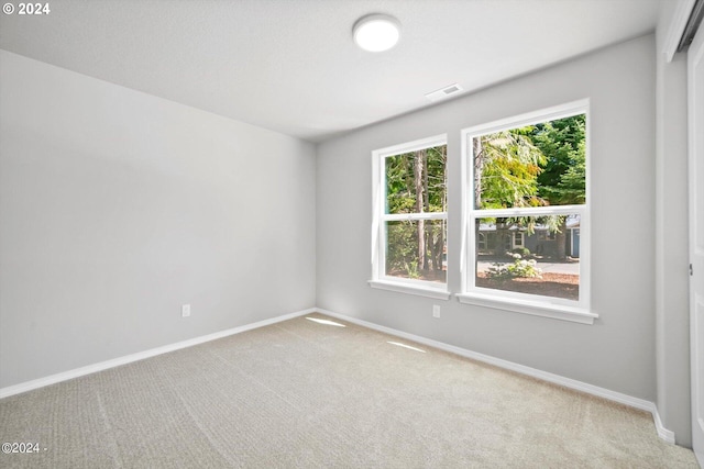 carpeted spare room featuring visible vents and baseboards