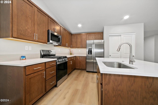 kitchen with brown cabinetry, a sink, stainless steel appliances, light countertops, and light wood-type flooring