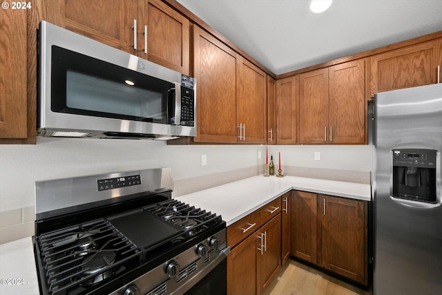 kitchen with brown cabinetry, stainless steel appliances, and light countertops