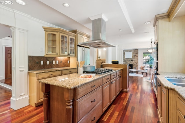 kitchen featuring island exhaust hood, backsplash, a center island, dark wood finished floors, and decorative columns