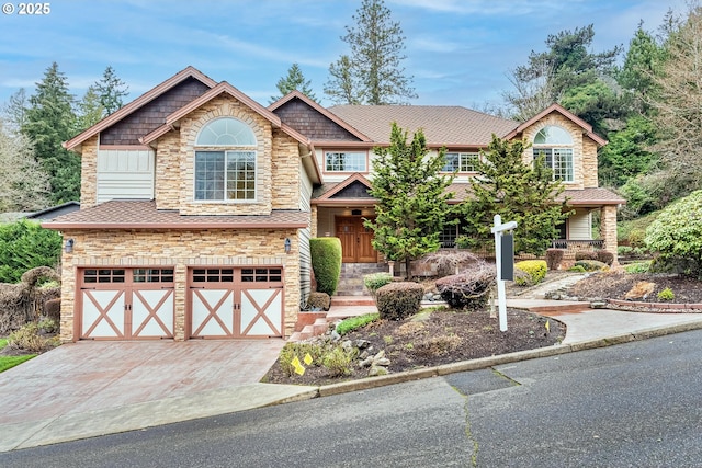 view of front of home featuring an attached garage, stone siding, driveway, and a shingled roof