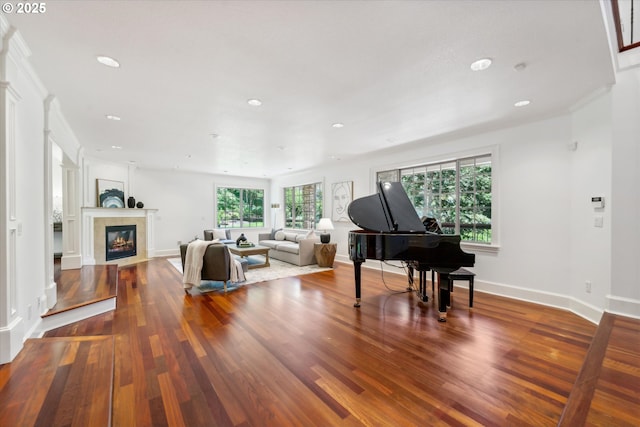 living room featuring a glass covered fireplace, recessed lighting, wood finished floors, and baseboards