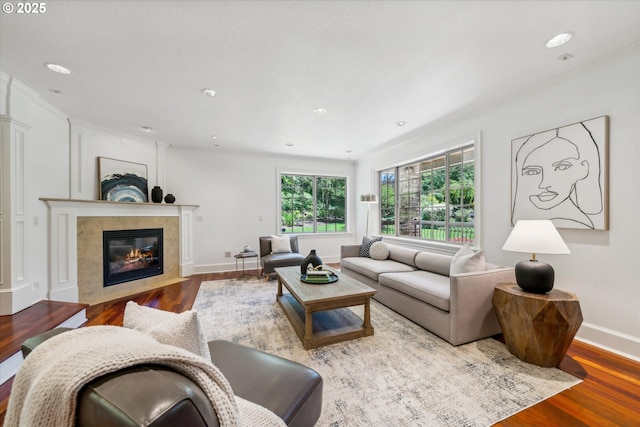 living room with a tile fireplace, baseboards, and wood finished floors