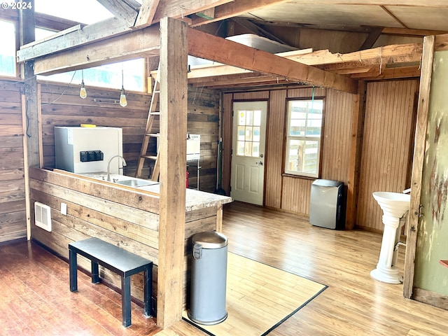 misc room with wood-type flooring, lofted ceiling, plenty of natural light, and wooden walls