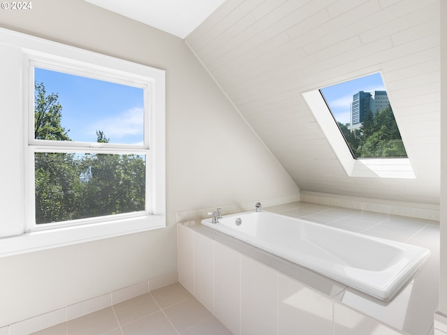 bathroom featuring a healthy amount of sunlight, vaulted ceiling with skylight, and tile patterned floors