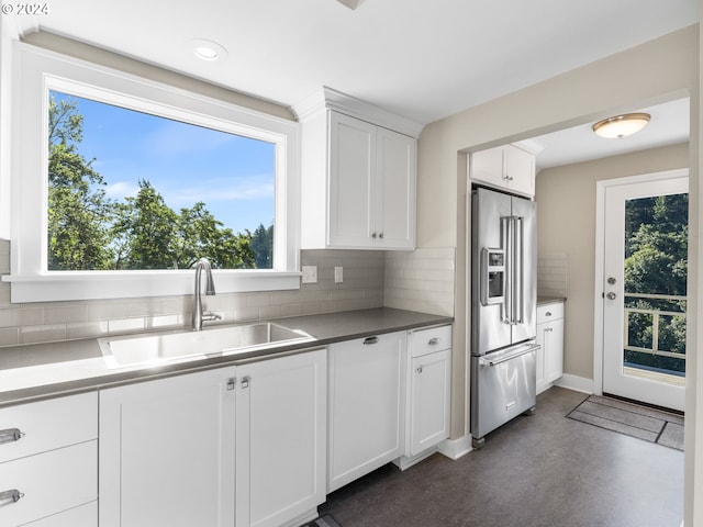 kitchen featuring decorative backsplash, sink, high quality fridge, and white cabinetry