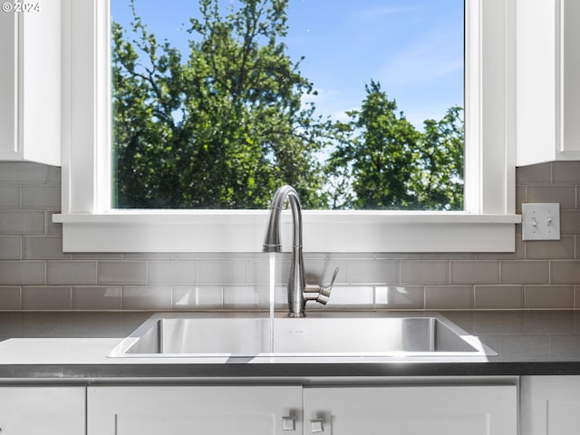 interior details featuring white cabinetry, sink, and backsplash