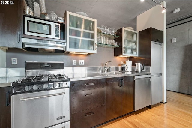 kitchen with dark brown cabinetry, sink, stainless steel counters, light wood-type flooring, and stainless steel appliances