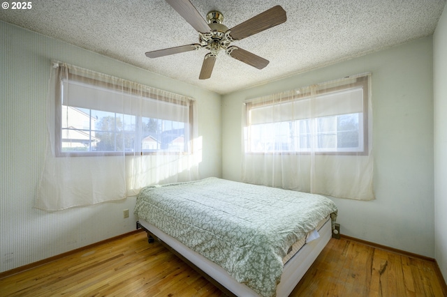 bedroom featuring ceiling fan, a textured ceiling, and light wood-type flooring