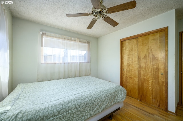 bedroom featuring ceiling fan, wood-type flooring, a closet, and a textured ceiling