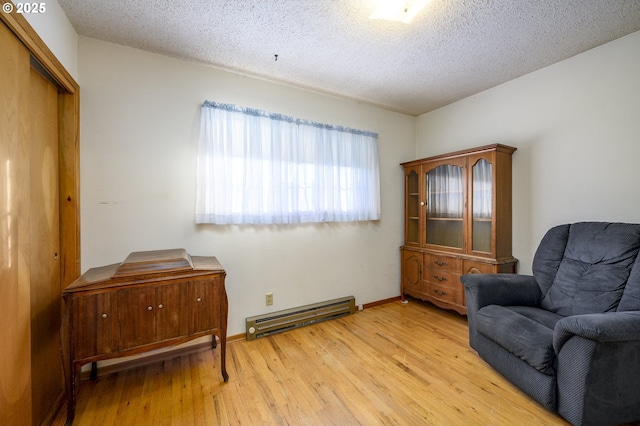 sitting room with a baseboard radiator, a textured ceiling, and light wood-type flooring