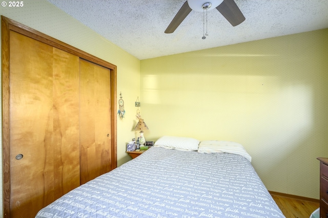 bedroom with hardwood / wood-style flooring, ceiling fan, a textured ceiling, and a closet