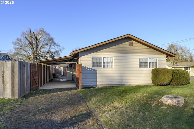 view of side of home featuring a yard, a patio area, and a carport