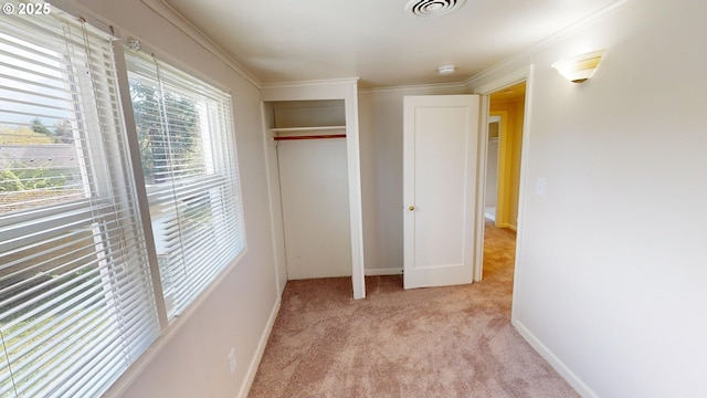 unfurnished bedroom with a closet, ornamental molding, and light carpet