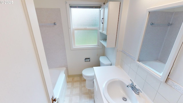 bathroom featuring a tub to relax in, sink, and toilet