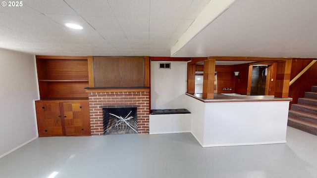 unfurnished living room with a brick fireplace, built in features, and concrete floors