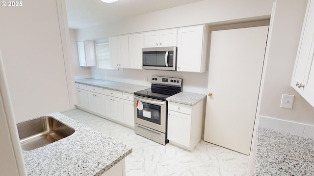 kitchen with appliances with stainless steel finishes, sink, white cabinets, and light stone counters