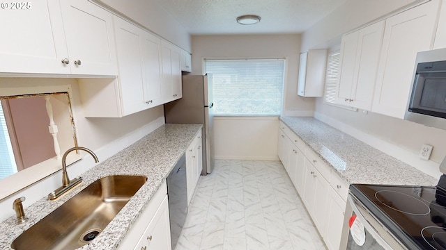 kitchen with light stone countertops, appliances with stainless steel finishes, sink, and white cabinets