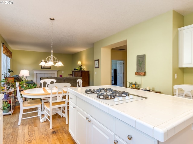 15337 SE Olds Dr, Clackamas, OR 97015 - kitchen featuring tile counters, white gas stovetop, light wood-type flooring, a chandelier, and a textured ceiling