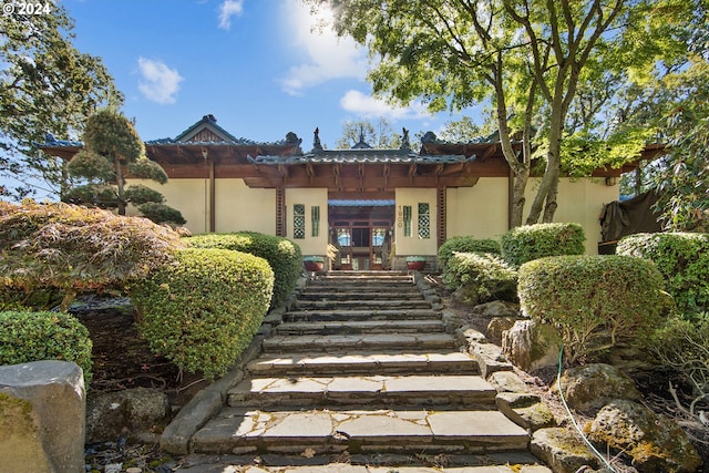 rear view of property with a tiled roof and stucco siding