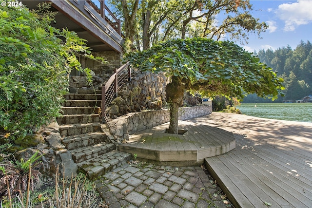 wooden terrace with a water view and stairs