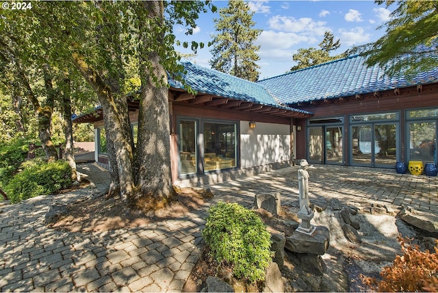 rear view of house with a tiled roof and a patio