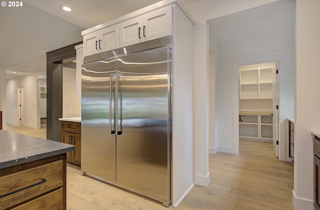 kitchen with built in refrigerator, light hardwood / wood-style flooring, and white cabinets