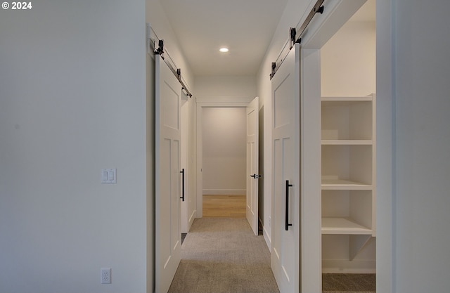 hall featuring light carpet and a barn door